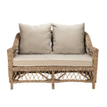 Wicker loveseat with beige cushions on a white background