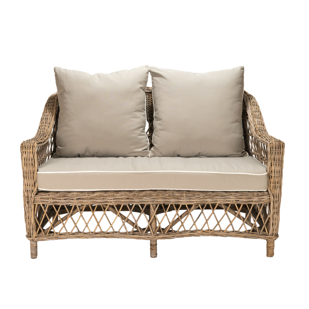 Wicker loveseat with beige cushions on a white background