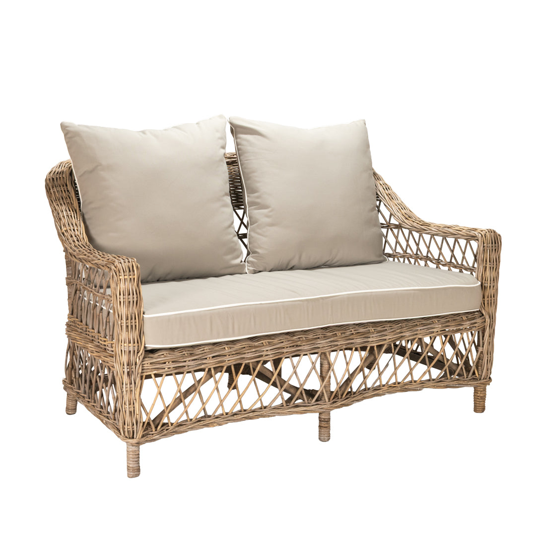Wicker loveseat with beige cushions on a white background