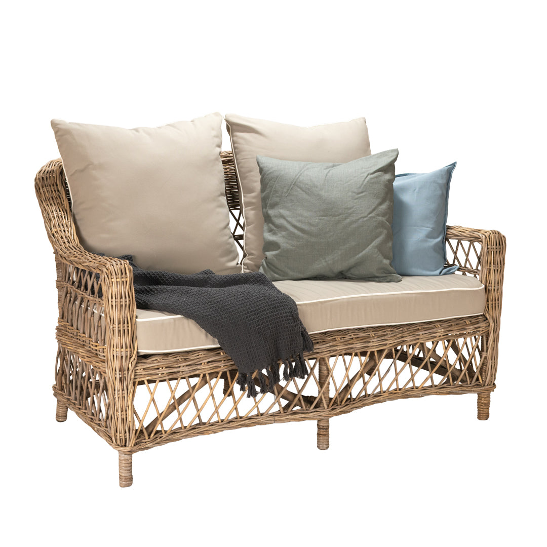 Wicker outdoor sofa with cushions and a blanket on a white background
